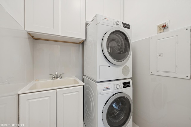 washroom featuring a sink, cabinet space, electric panel, and stacked washer / dryer