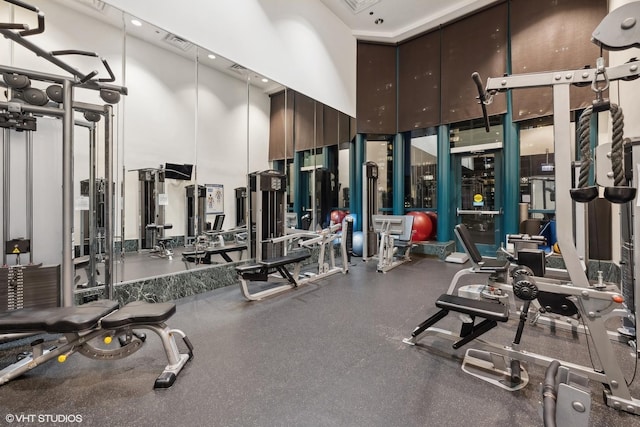 exercise room with visible vents and a towering ceiling