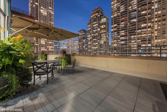 view of patio featuring outdoor dining area and a view of city lights