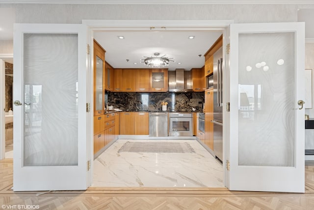 kitchen with dark countertops, wall chimney exhaust hood, appliances with stainless steel finishes, brown cabinets, and glass insert cabinets