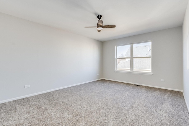 carpeted empty room with baseboards, visible vents, and a ceiling fan