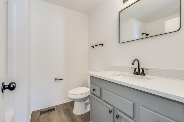 full bath with visible vents, toilet, vanity, wood finished floors, and baseboards