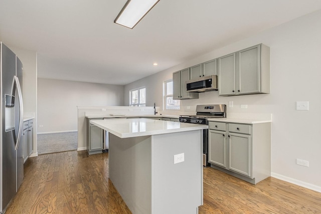 kitchen with stainless steel appliances, light countertops, gray cabinets, and dark wood-type flooring