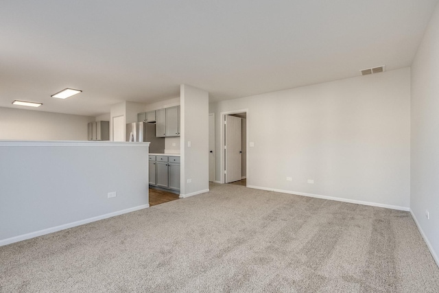 carpeted empty room featuring baseboards and visible vents