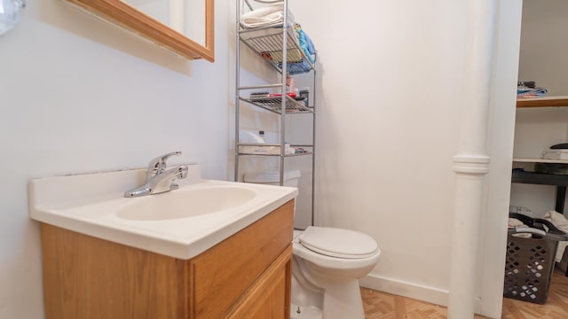 half bathroom featuring vanity, toilet, and baseboards