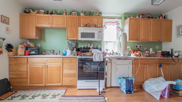 kitchen featuring light countertops, white microwave, light wood-type flooring, and range