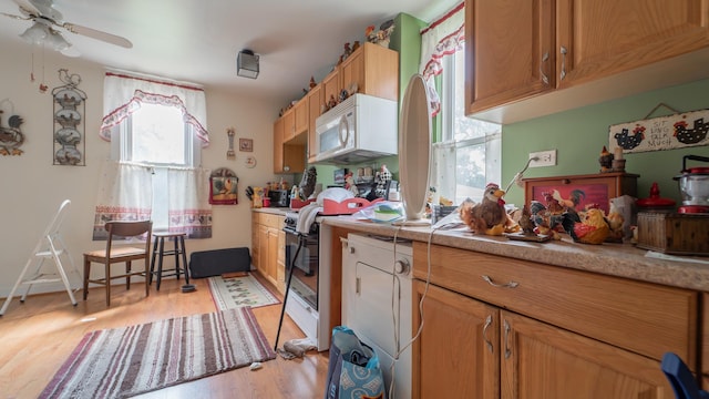 kitchen featuring white microwave, electric range, a ceiling fan, light countertops, and light wood finished floors