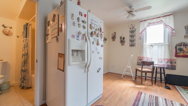 kitchen with white fridge with ice dispenser, light wood-type flooring, baseboards, and a ceiling fan