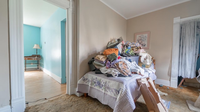 bedroom featuring ornamental molding, baseboards, and wood finished floors