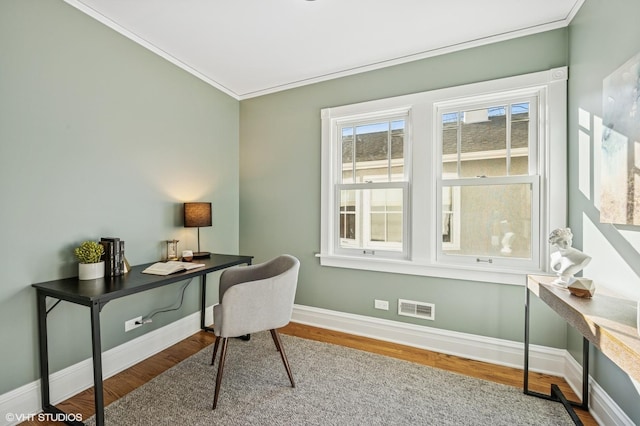 office space featuring baseboards, wood finished floors, visible vents, and ornamental molding