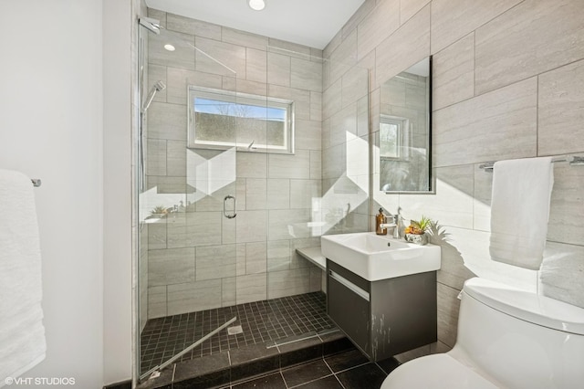 full bathroom with a shower stall, toilet, vanity, tile patterned floors, and tile walls