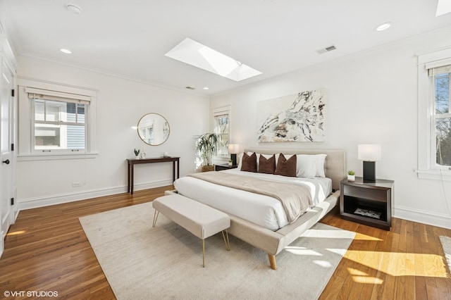 bedroom with visible vents, wood finished floors, a skylight, and crown molding