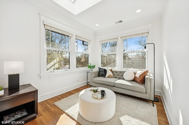 interior space featuring visible vents, a skylight, wood finished floors, and ornamental molding