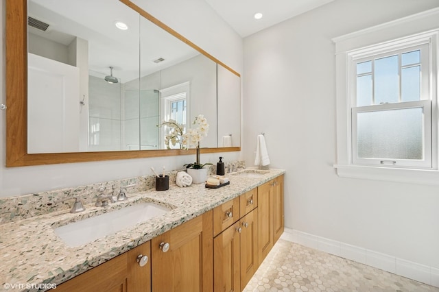 bathroom with an enclosed shower, visible vents, a sink, double vanity, and baseboards