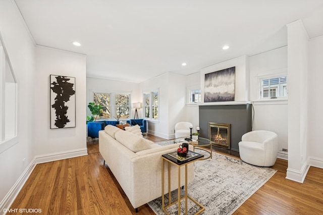 living room featuring recessed lighting, baseboards, wood finished floors, and a glass covered fireplace