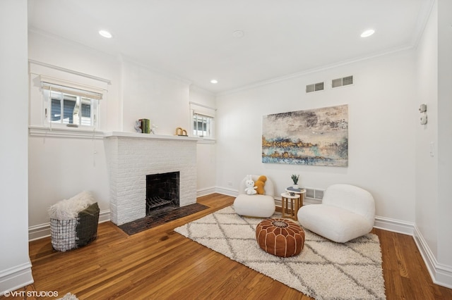 sitting room featuring visible vents, baseboards, wood finished floors, and crown molding