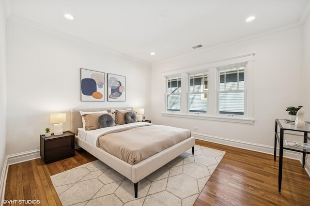 bedroom featuring visible vents, wood finished floors, baseboards, and ornamental molding