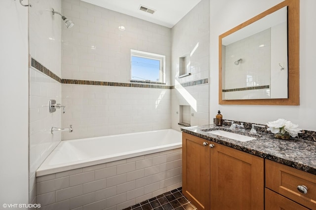 bathroom featuring vanity, tile patterned floors, tiled shower / bath, and visible vents