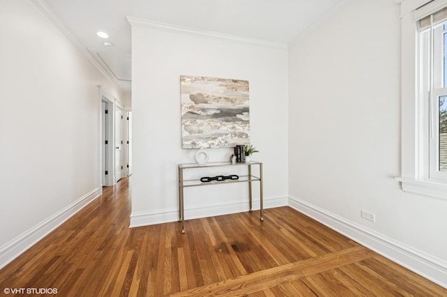 empty room with attic access, wood finished floors, and ornamental molding