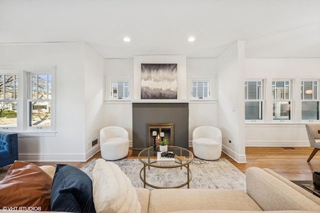 living room featuring recessed lighting, baseboards, wood finished floors, and a glass covered fireplace