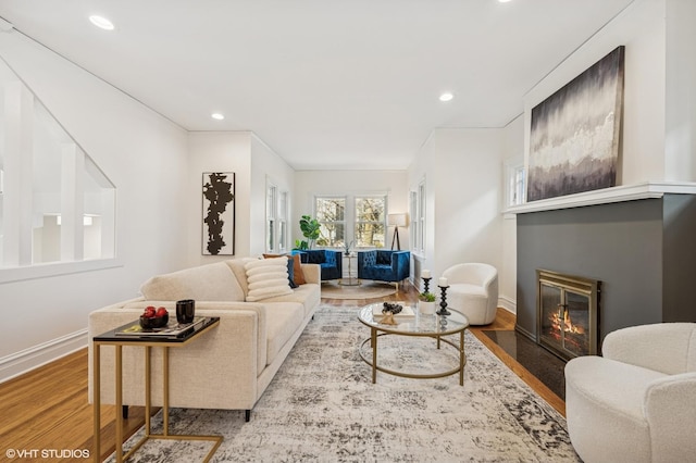 living area featuring recessed lighting, baseboards, a fireplace with flush hearth, and wood finished floors