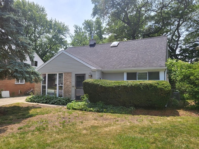 view of front of house featuring brick siding, a front lawn, and roof with shingles