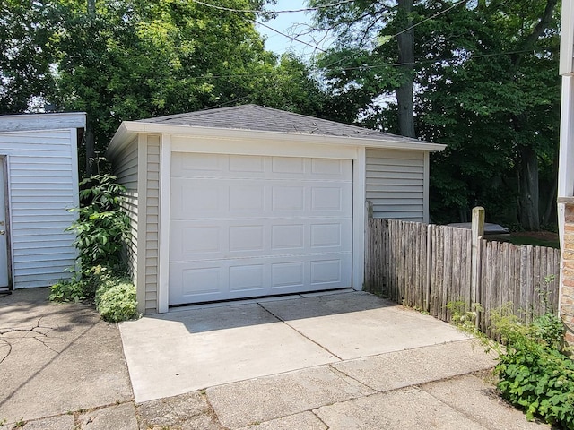 detached garage featuring driveway and fence