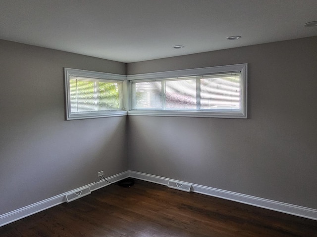 empty room featuring baseboards, visible vents, dark wood-style flooring, and recessed lighting