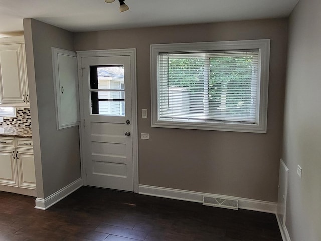 doorway to outside featuring dark wood-style flooring, visible vents, and baseboards