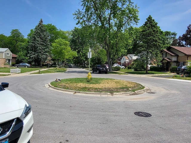 view of road featuring traffic signs, a residential view, and curbs