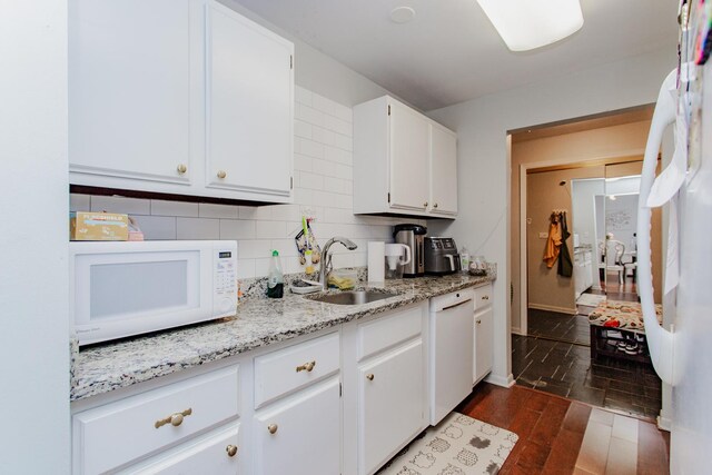 kitchen with dark wood finished floors, decorative backsplash, white appliances, white cabinetry, and a sink