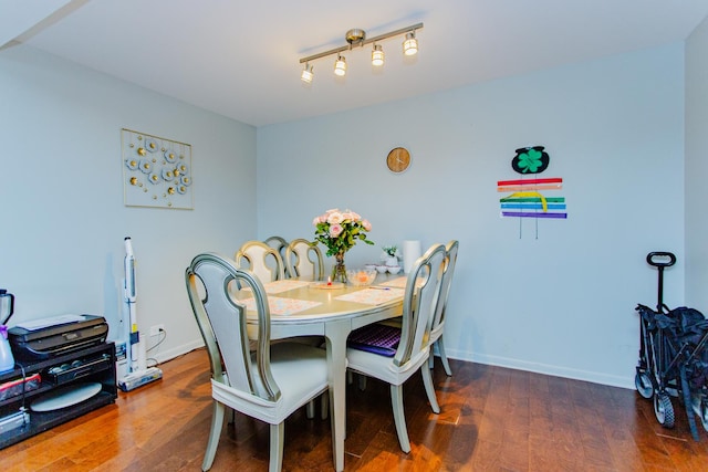 dining space featuring rail lighting, baseboards, and wood finished floors