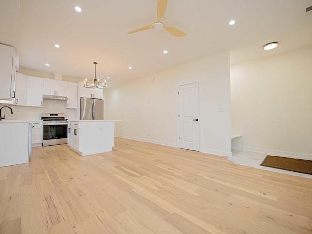 kitchen featuring under cabinet range hood, stainless steel appliances, a kitchen island, a sink, and light wood-type flooring