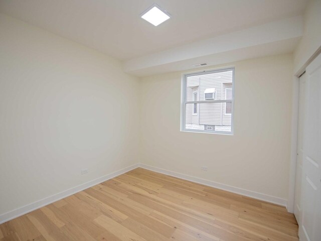 spare room with visible vents, light wood-style flooring, and baseboards