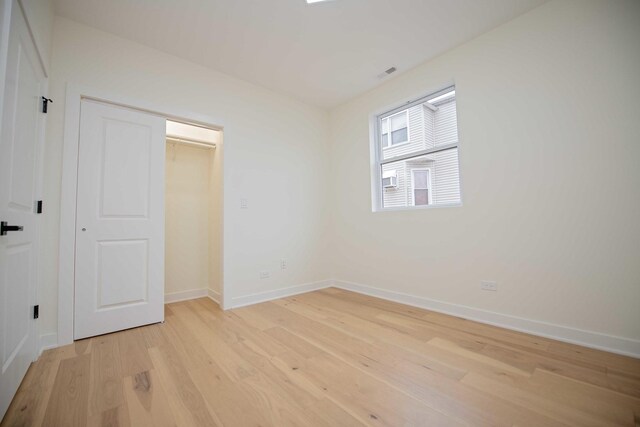 unfurnished bedroom featuring a closet, light wood-style flooring, and baseboards