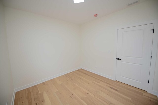 empty room featuring light wood-style floors, visible vents, and baseboards