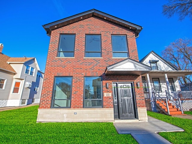 view of front of house with a front yard, covered porch, and brick siding