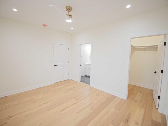 unfurnished bedroom with a spacious closet, recessed lighting, light wood-style flooring, and baseboards