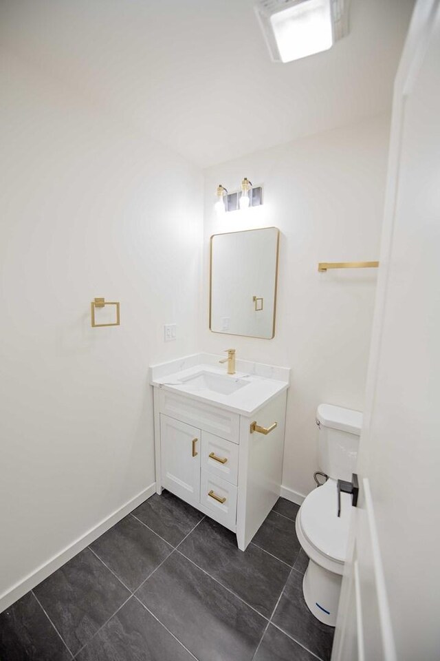 bathroom featuring baseboards, vanity, toilet, and tile patterned floors