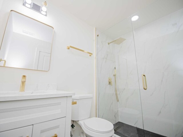 bathroom with toilet, vanity, and a marble finish shower