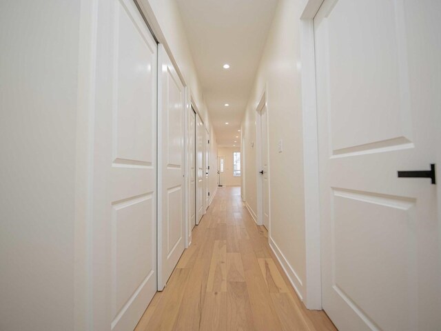 corridor with light wood-type flooring, baseboards, and recessed lighting