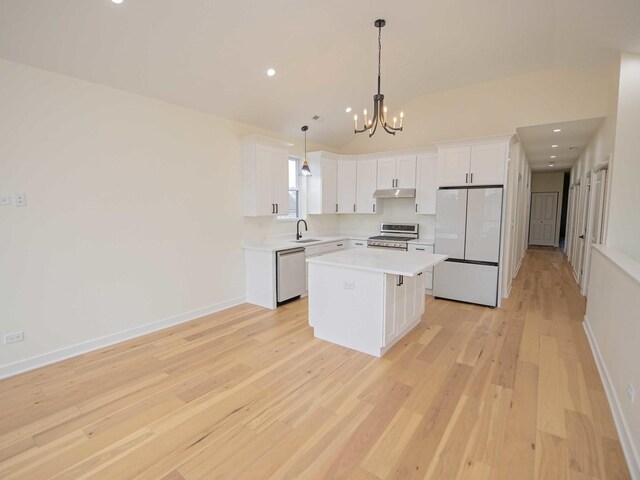 kitchen with white cabinets, stainless steel appliances, light countertops, under cabinet range hood, and a sink