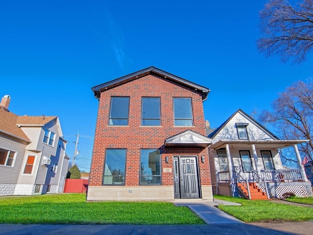 view of front facade with covered porch, a front yard, and brick siding