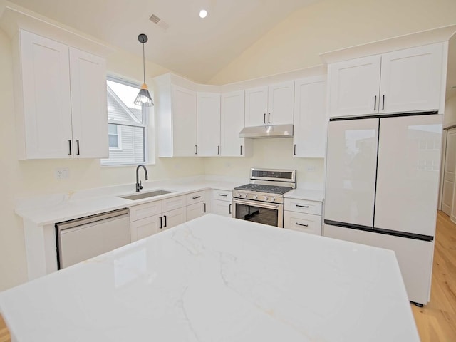 kitchen with dishwasher, freestanding refrigerator, a sink, under cabinet range hood, and stainless steel range with gas stovetop