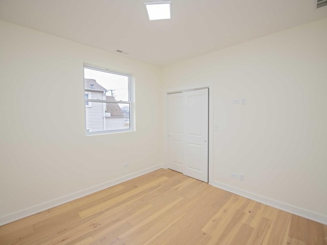 spare room featuring light wood-type flooring and baseboards