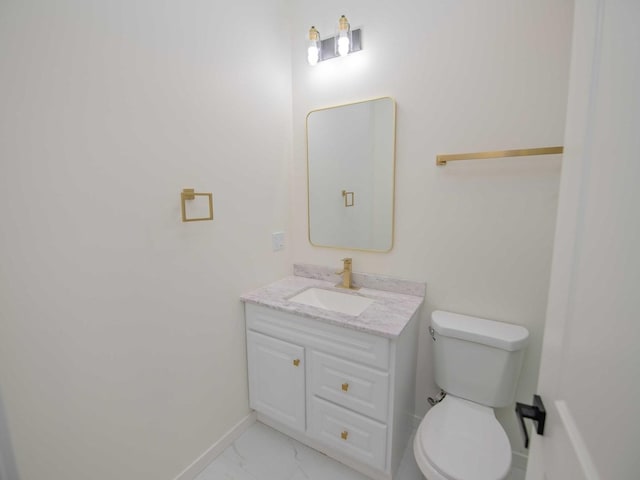 half bathroom featuring toilet, marble finish floor, baseboards, and vanity