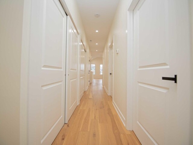 corridor with baseboards, light wood-type flooring, and recessed lighting