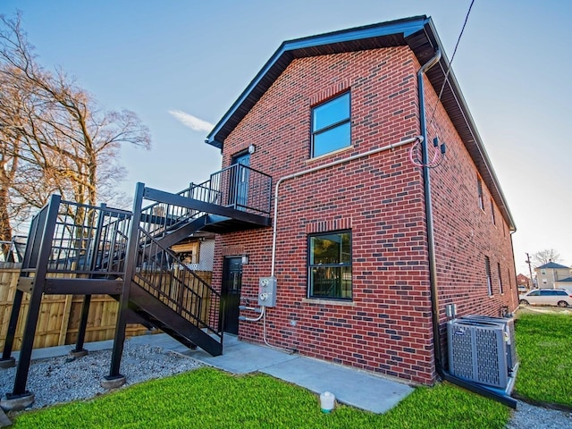 exterior space with stairs, brick siding, and cooling unit