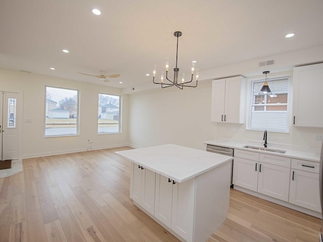 kitchen featuring a kitchen island, light wood-style floors, visible vents, and a sink