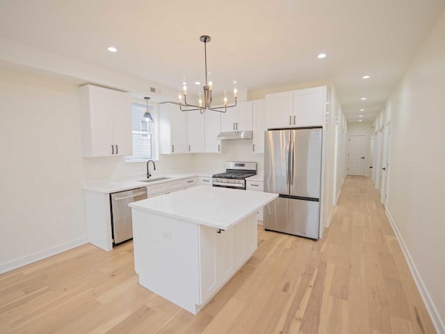 kitchen with appliances with stainless steel finishes, white cabinets, a sink, and a center island